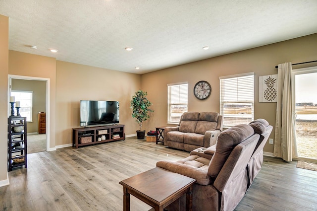 living room with light wood finished floors, baseboards, a textured ceiling, and recessed lighting