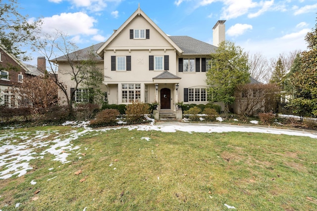 view of front of house with a front yard, roof with shingles, a chimney, and stucco siding