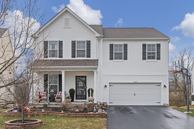 traditional-style home featuring a porch, a shingled roof, an attached garage, and aphalt driveway