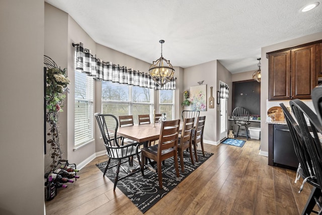 dining room featuring a chandelier, a textured ceiling, hardwood / wood-style flooring, and baseboards