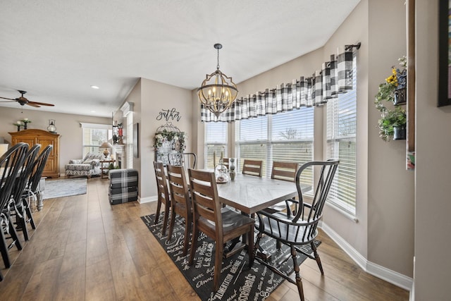 dining room featuring baseboards, wood finished floors, and ceiling fan with notable chandelier