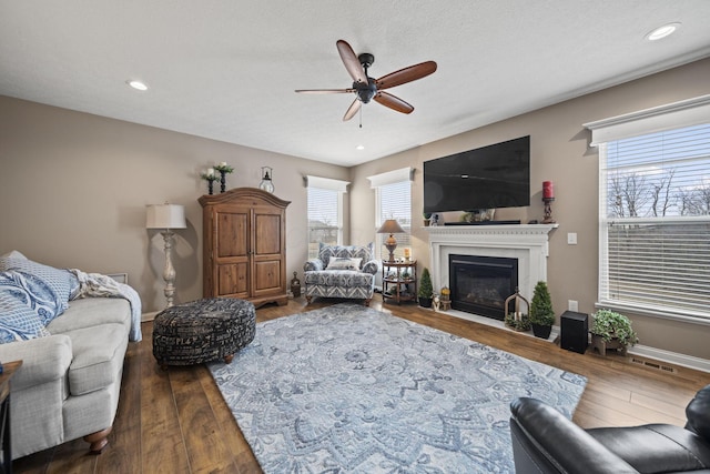 living area with baseboards, wood finished floors, and a glass covered fireplace