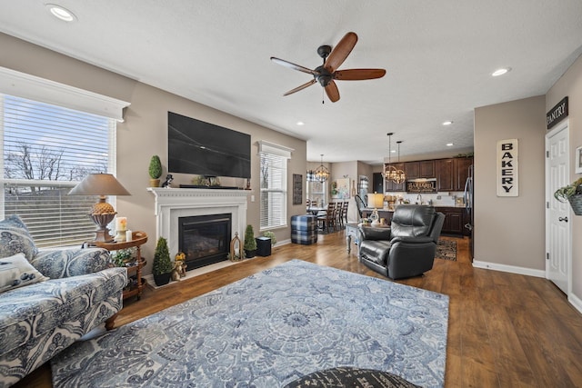 living area with dark wood finished floors, recessed lighting, a fireplace with flush hearth, ceiling fan, and baseboards