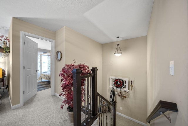 corridor with carpet floors, baseboards, and an upstairs landing