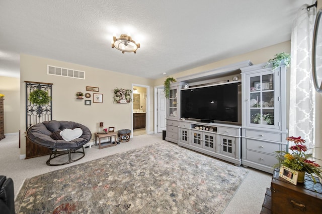 carpeted living area featuring visible vents, a textured ceiling, and baseboards