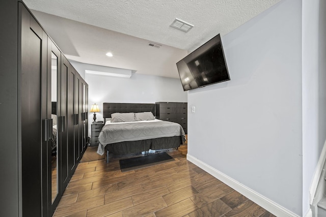 bedroom featuring a textured ceiling, wood finished floors, visible vents, and baseboards