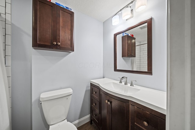 bathroom with toilet, a textured ceiling, vanity, wood finished floors, and baseboards