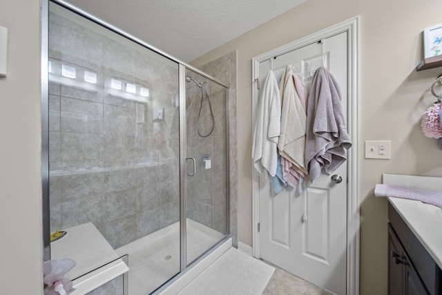 full bathroom featuring a textured ceiling, a stall shower, vanity, and tile patterned floors