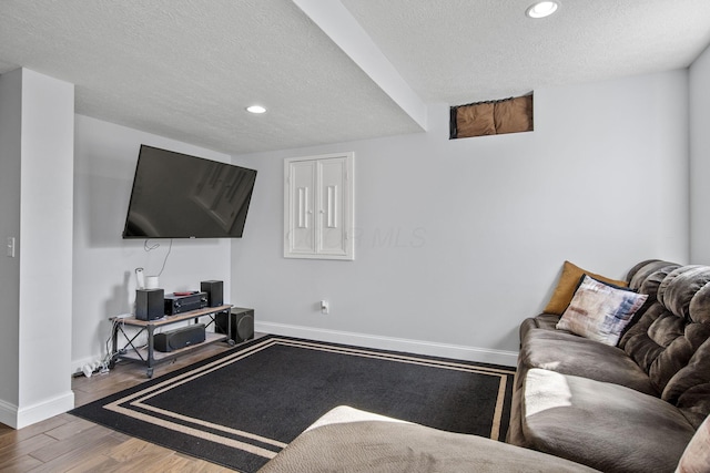 living room featuring a textured ceiling, baseboards, wood finished floors, and recessed lighting