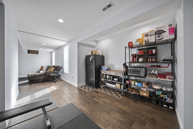 workout room featuring a textured ceiling, recessed lighting, wood finished floors, visible vents, and baseboards