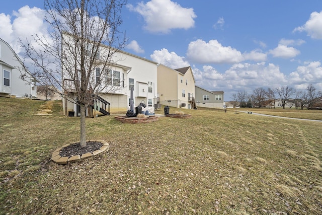 rear view of property featuring a residential view, stairway, and a yard