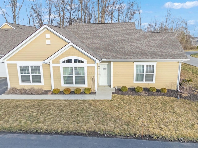 view of front of property with a shingled roof and a front lawn