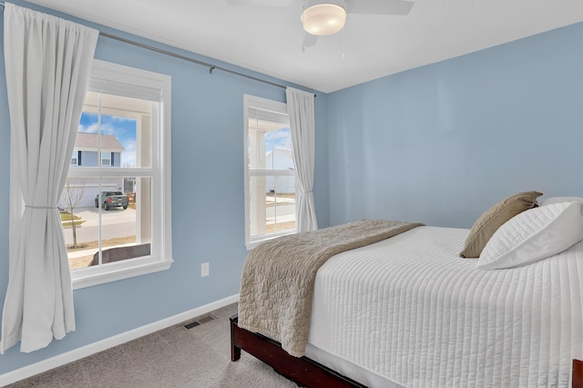 bedroom featuring carpet, multiple windows, visible vents, and baseboards