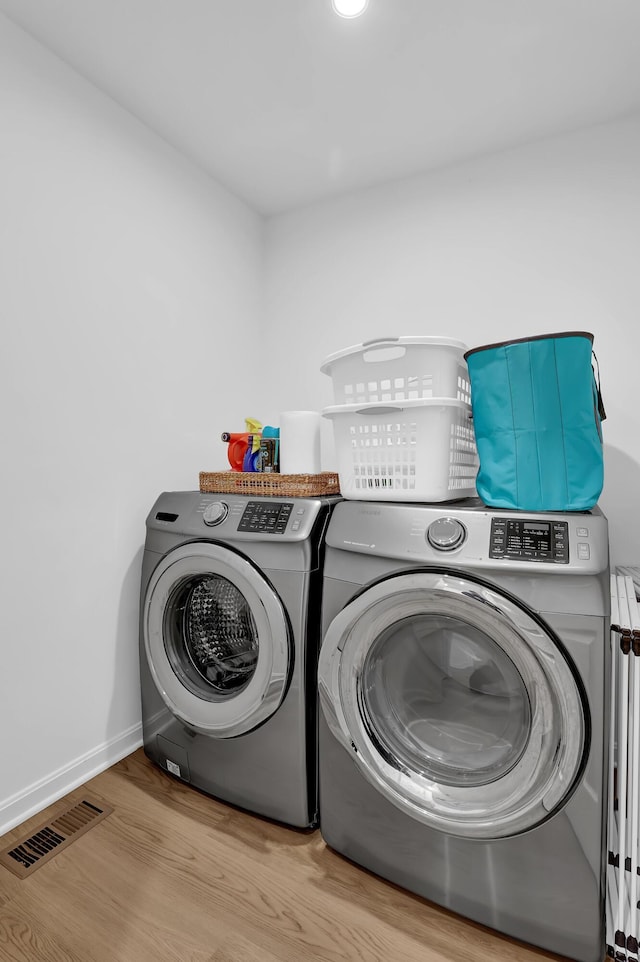 clothes washing area with laundry area, baseboards, visible vents, wood finished floors, and independent washer and dryer