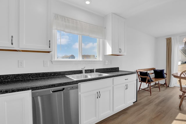 kitchen with a sink, white cabinets, stainless steel dishwasher, light wood finished floors, and dark countertops