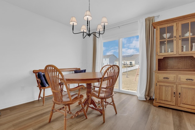 dining room with light wood-style flooring and a notable chandelier