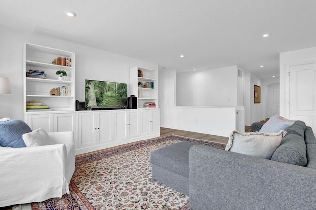 living area with built in shelves, wood finished floors, and recessed lighting