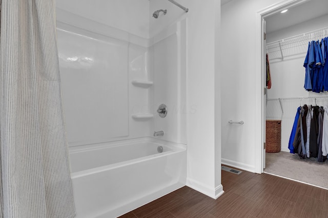 bathroom featuring  shower combination, a walk in closet, visible vents, and baseboards