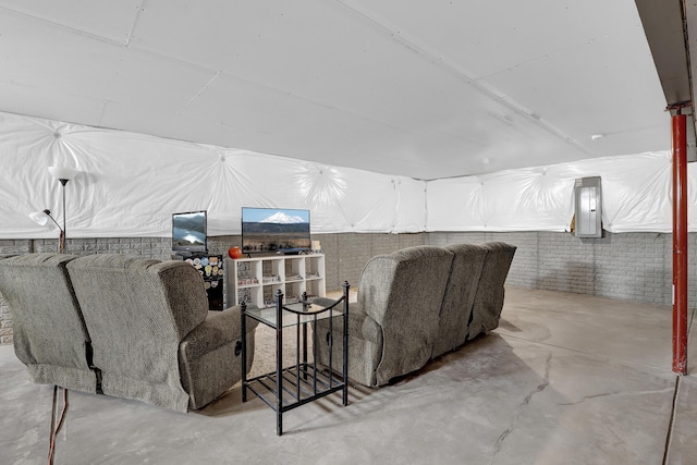 home theater room with electric panel, concrete floors, and brick wall