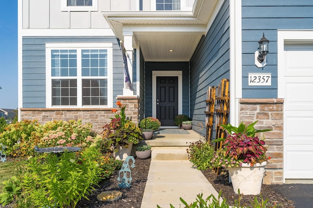 property entrance with a garage, stone siding, and board and batten siding