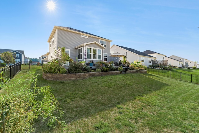 back of house featuring a fenced backyard, a residential view, a lawn, and a patio