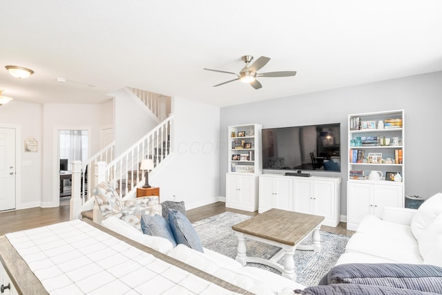 living area with ceiling fan, stairs, baseboards, and wood finished floors