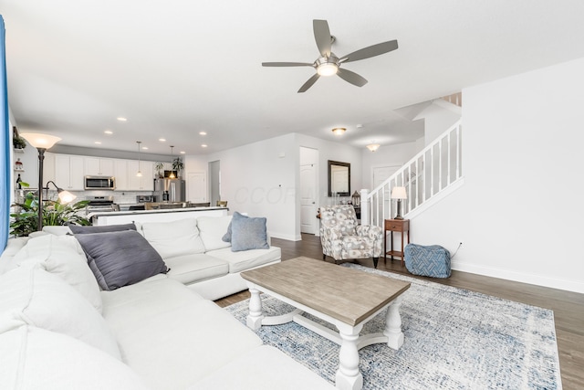 living area with baseboards, stairway, and wood finished floors