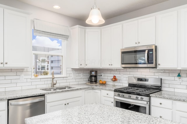 kitchen with appliances with stainless steel finishes, a sink, white cabinetry, and tasteful backsplash