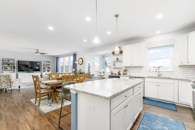 kitchen featuring wood finished floors, backsplash, a sink, and a center island