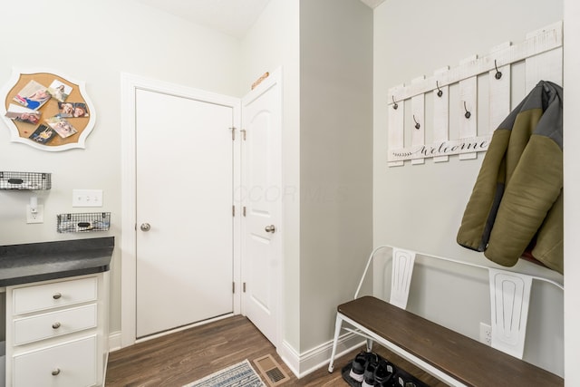 mudroom featuring visible vents, baseboards, and dark wood-type flooring