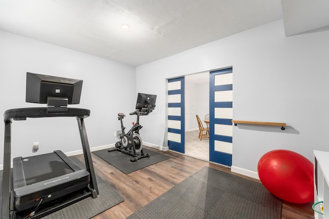 workout area featuring baseboards and wood finished floors