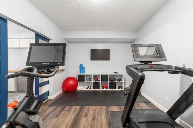 exercise area featuring baseboards and wood finished floors