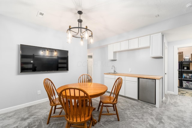 dining room featuring baseboards, a notable chandelier, visible vents, and light colored carpet