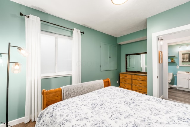 bedroom featuring connected bathroom, baseboards, and wood finished floors