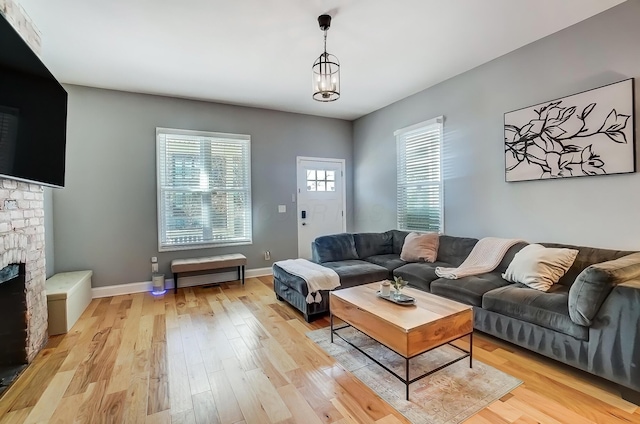 living area with light wood finished floors, a fireplace, and baseboards