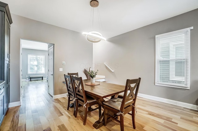 dining room with a notable chandelier, light wood finished floors, and baseboards