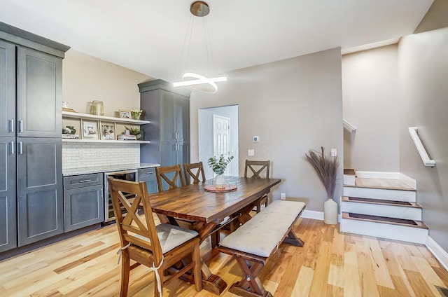 dining room featuring light wood-style floors, beverage cooler, stairs, and baseboards