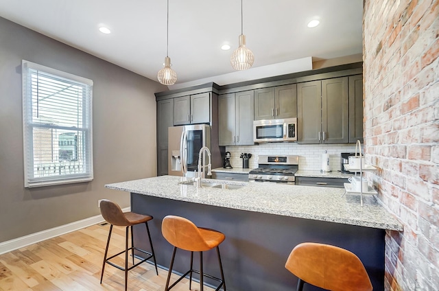 kitchen featuring baseboards, decorative backsplash, a kitchen breakfast bar, stainless steel appliances, and a sink