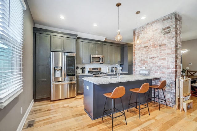 kitchen with appliances with stainless steel finishes, a healthy amount of sunlight, a sink, and a kitchen breakfast bar