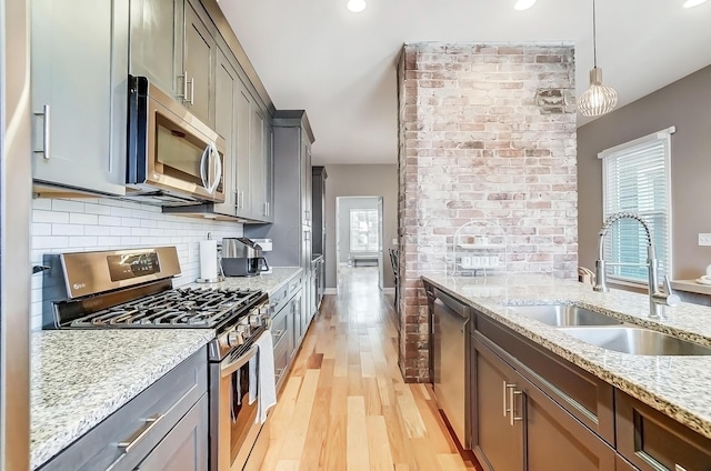 kitchen featuring stainless steel appliances, light stone counters, backsplash, and a sink