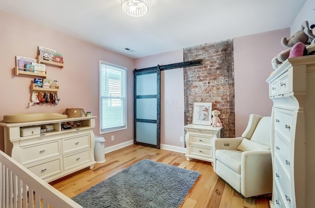 bedroom featuring baseboards, a barn door, visible vents, and light wood-style floors