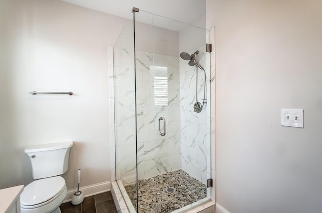 bathroom featuring toilet, a marble finish shower, and baseboards