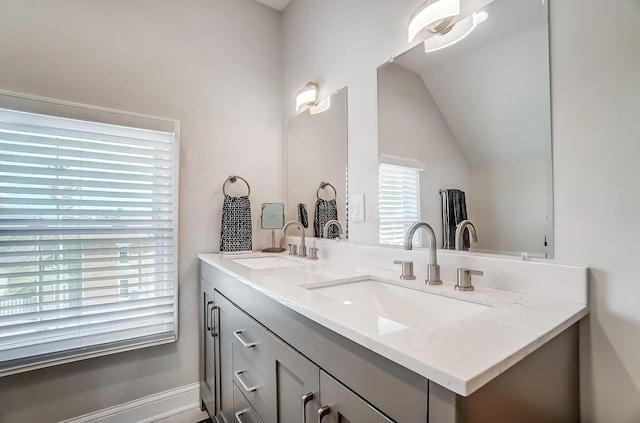 bathroom with lofted ceiling, a sink, and double vanity