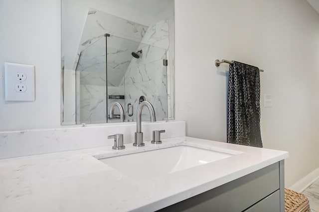 full bath featuring a marble finish shower and vanity