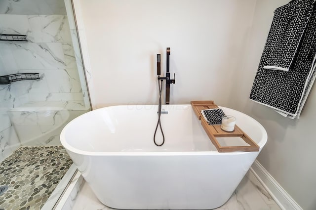 bathroom featuring marble finish floor, baseboards, a freestanding bath, and tiled shower