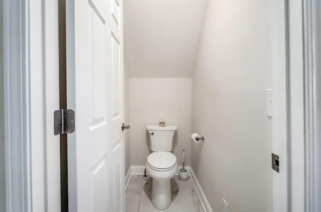 bathroom featuring lofted ceiling, marble finish floor, baseboards, and toilet