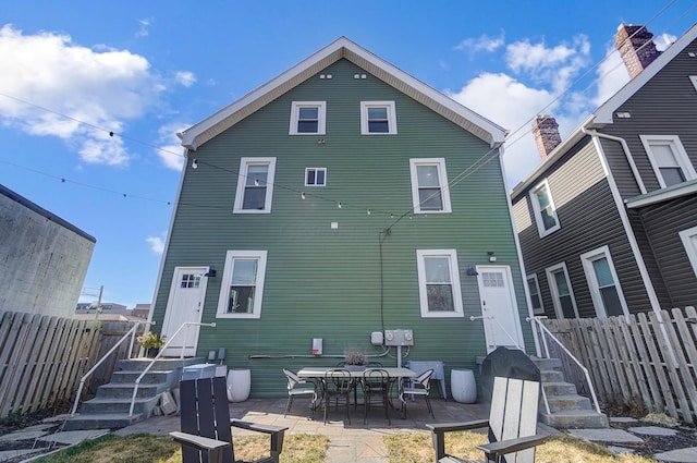 back of property with fence and a patio