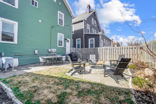 rear view of house with fence, a fire pit, and a patio