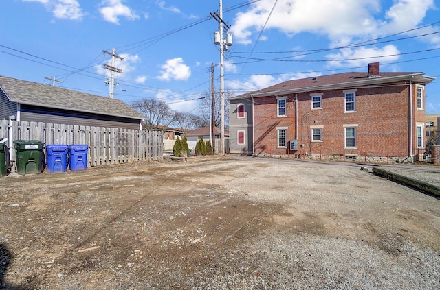 exterior space featuring a chimney, fence, and brick siding