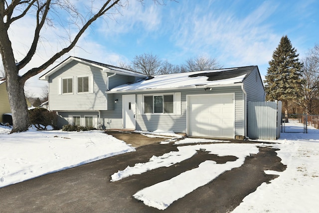 split level home with a garage, a gate, and fence